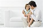 Männlichen Arzt im Gespräch mit jungen Patienten, Mädchen auf seinem Schoß sitzen