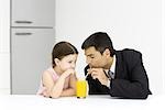 Little girl and father drinking from glass of juice together