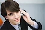 Young man in suit using cell phone, smiling at camera, high angle view