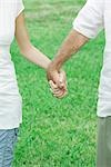 Couple holding hands outdoors, cropped view