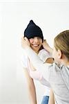 Femme tirant sur tricoter un chapeau sur la tête de son amie