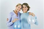 Mother and teen son with arms around each other's shoulders, holding balloons, smiling at camera