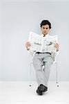 Businessman slouching in chair, reading newspaper