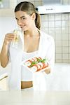 Young woman holding tomato and mozzarella salad, smelling salad dressing