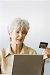 Senior woman making on-line purchase, looking at credit card