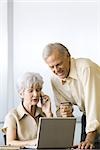 Couple d'âge mûr achat de carte de crédit, à l'aide d'ordinateur portable et téléphone cellulaire