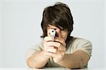 Young man aiming gun at camera