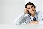 Young man using cell phone, looking up, smiling