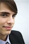 Young man in suit, smiling at camera, portrait, cropped