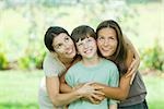 Mother embracing son and teen daughter, all smiling and looking up