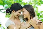 Mother and teen daughter embracing, smiling at each other, touching foreheads