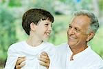 Grandfather and grandson smiling at each other, man holding boy