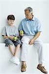 Großvater und Enkel zusammensitzen auf Sims, beide halten Äpfel