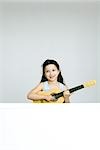 Little girl playing toy guitar, smiling