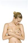 Femme tenant silicone implants sur seins, regardant vers le bas, souriant