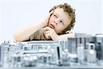 Little boy next to circuit board, holding head, looking up