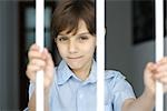 Boy behind bars, smiling at camera