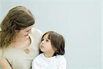 Mother and young son looking at each other, boy frowning