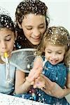 Jeune femme et deux petites filles, jetant des confettis, tout souriant