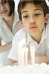 Boy blowing out candles on birthday cake, close-up
