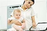 Woman holding baby, using cell phone and looking at agenda