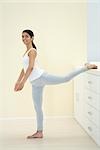 Woman stretching, leg up, smiling at camera