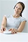 Woman listening to CD player with headphones, smiling at camera