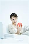 Young woman holding apple, looking down