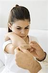 Man putting adhesive bandage on girl's elbow, cropped view