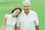 Grandfather with teenage granddaughter, her head on his shoulder, both smiling