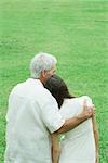 Grandfather with teenage granddaughter, arm around her shoulder, her head on his shoulder