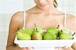 Woman holding plate of green pears, close-up