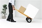 Businessman moving boxes with hand truck