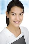 Young woman holding folder, smiling, portrait