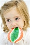 Toddler girl eating large lollipop, looking away