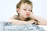 Little boy leaning on elbow, contemplating computer motherboard