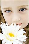 Little girl with blue eyes holding daisy, portrait, close-up