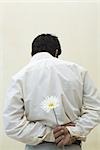 Man holding flower behind his back, rear view