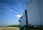 Semi-truck on highway, partial view, road and blue sky in background