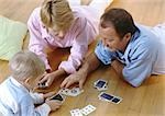 Parents playing cards with child, on floor, high angle view