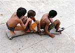 Three boys sitting on skateboards, elevated view