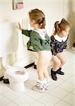 Two little girls using children's toilets