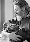 Mature man holding baby, side view, b&w