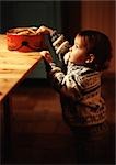Toddler reaching for cookies on table, side view
