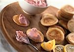 Blinis and taramasalata on round wooden board with lemon slice, close-up