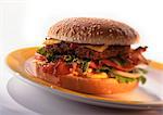 Cheeseburger with tomatoes, lettuce, and bacon on sesame seed bun, close-up