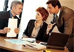 Two businessmen and a businesswoman around table