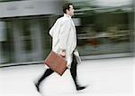 Businessman holding briefcase, running, blurred