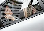 Unternehmer, die sitzen hinter dem Auto holding Zeitungs- und Handy, gesehen durch Fenster