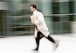 Businessman running in front of building, blurred